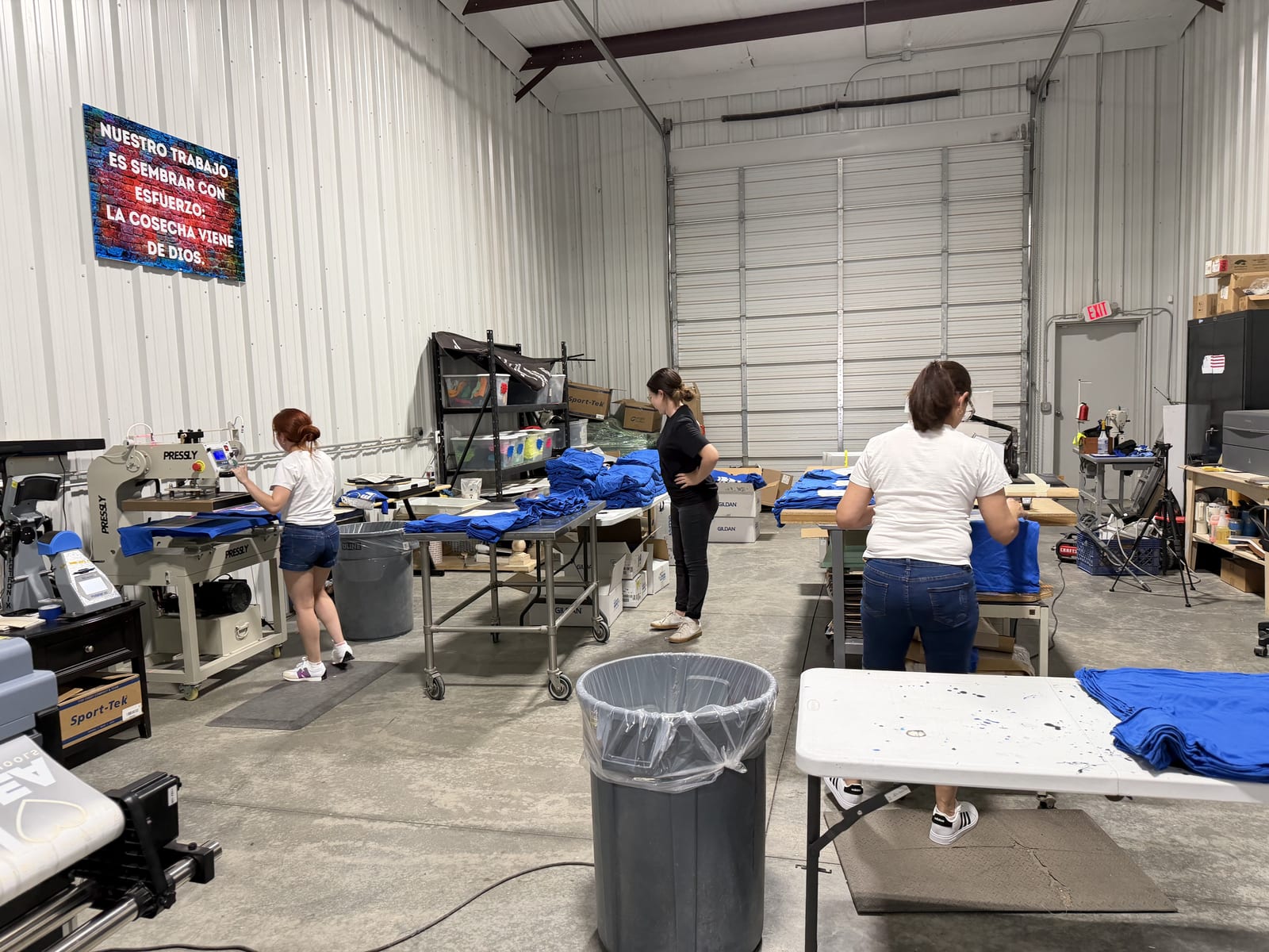 The Print A Vision production floor in Midland: automatic heat press, DTF printers, and staff working a bulk apparel run
