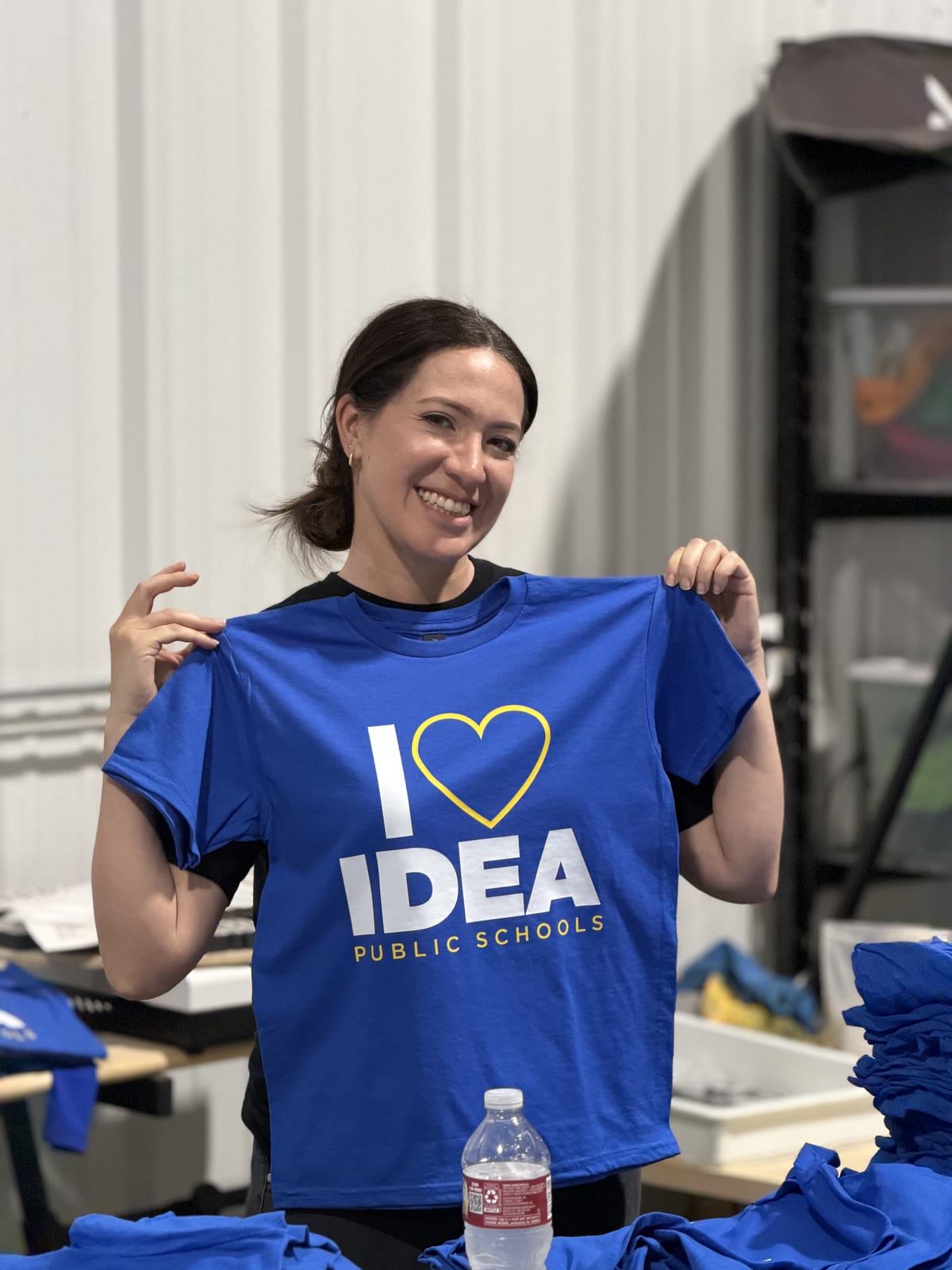 Staff member holding a freshly printed IDEA Public Schools tee